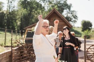 People celebrating outdoors near a rustic wooden barn on a sunny day.