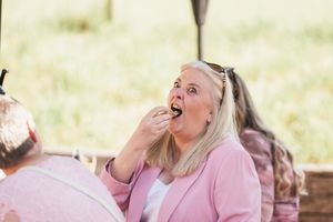 Wedding guest in pink blazer reacting with excitement and surprise during outdoor celebration.