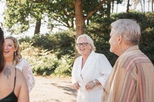 A joyful gathering of guests sharing a laugh at an outdoor wedding celebration.