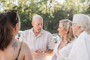 A group of people conversing outdoors during a sunny gathering or celebration with natural lighting in the background.