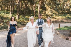 Group walking together down a wooded path wearing formal attire at an outdoor event.