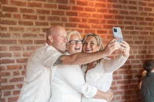 Group taking a selfie together against a brick wall at a celebration.