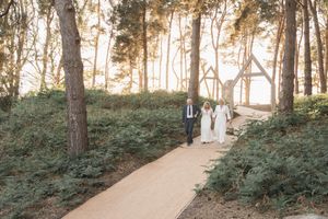 A couple walks down a wooded path during a romantic outdoor wedding photo session.