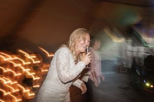 A person in a white lace dress dancing enthusiastically with motion blur and glowing light trails in the background.