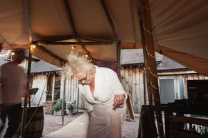 A couple shares their first dance under a white tent at an outdoor wedding reception.
