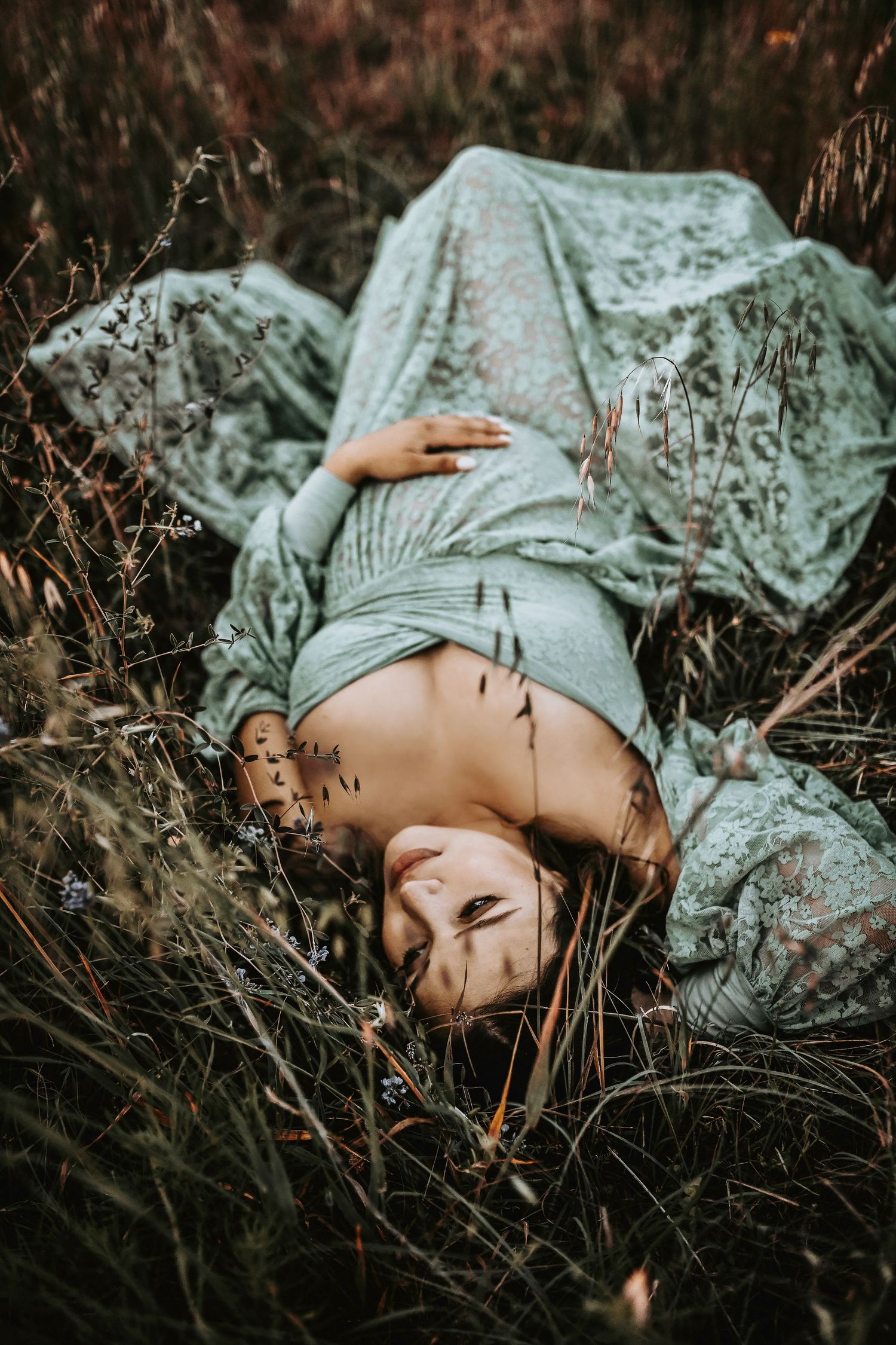beautiful maternity mother lays in a field for her maternity photos by april pinto photography