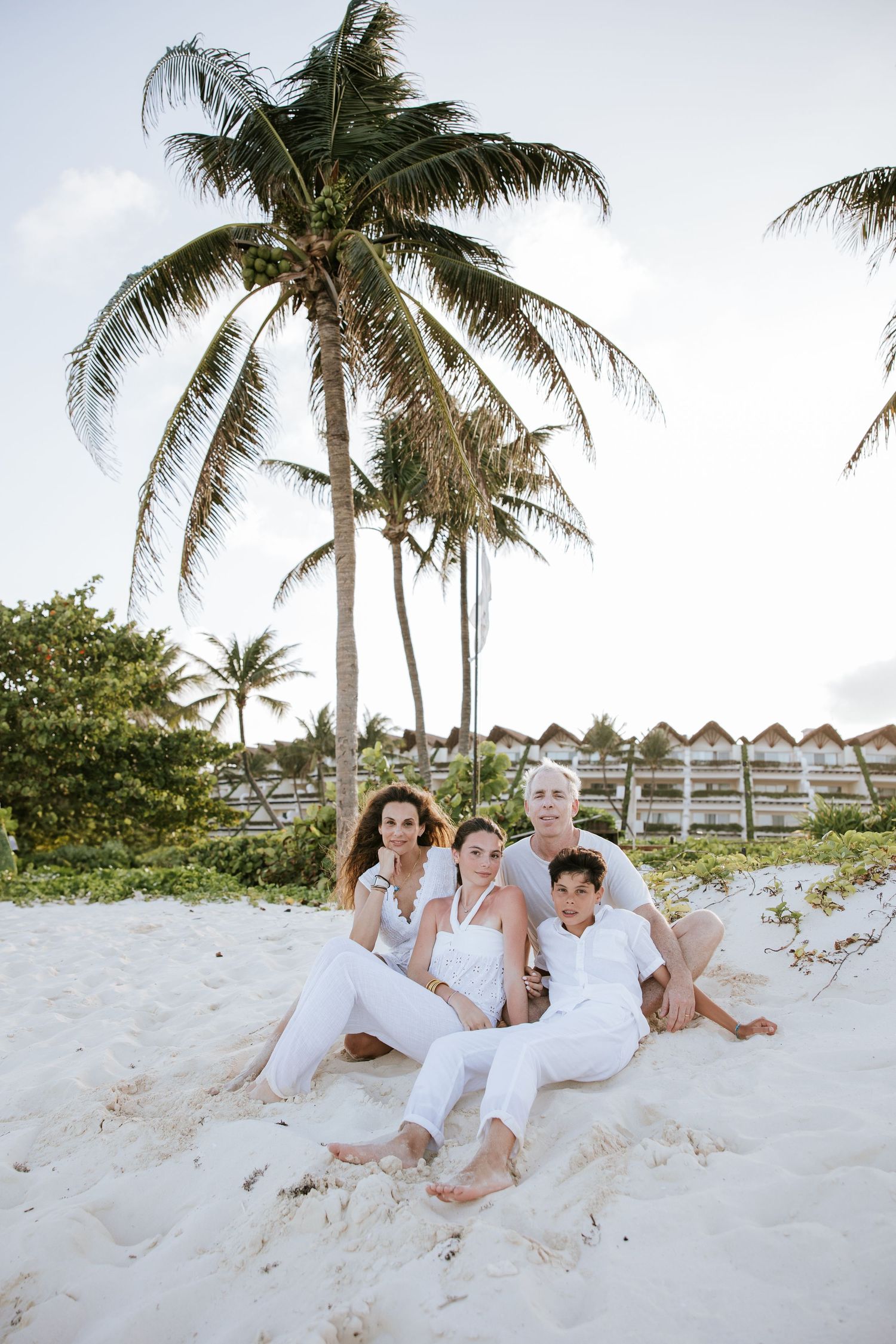 Family portrait at Grand Velas Riviera Maya. Sunset beach session with palm trees, white sand, and ocean. Riviera Maya family photographer