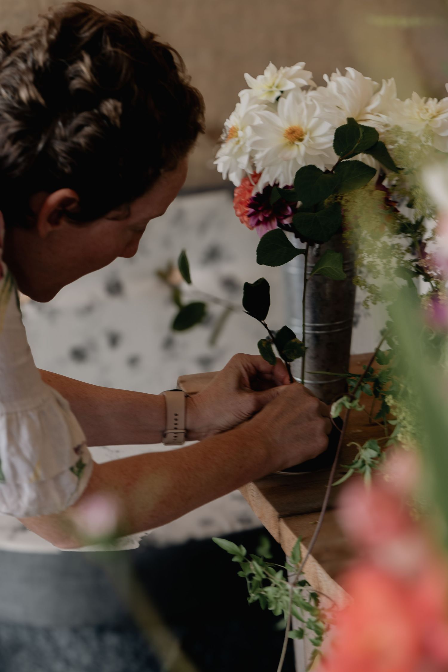 a photograph of a flower farmer arranging flowers in a vase within a workshop - event photography