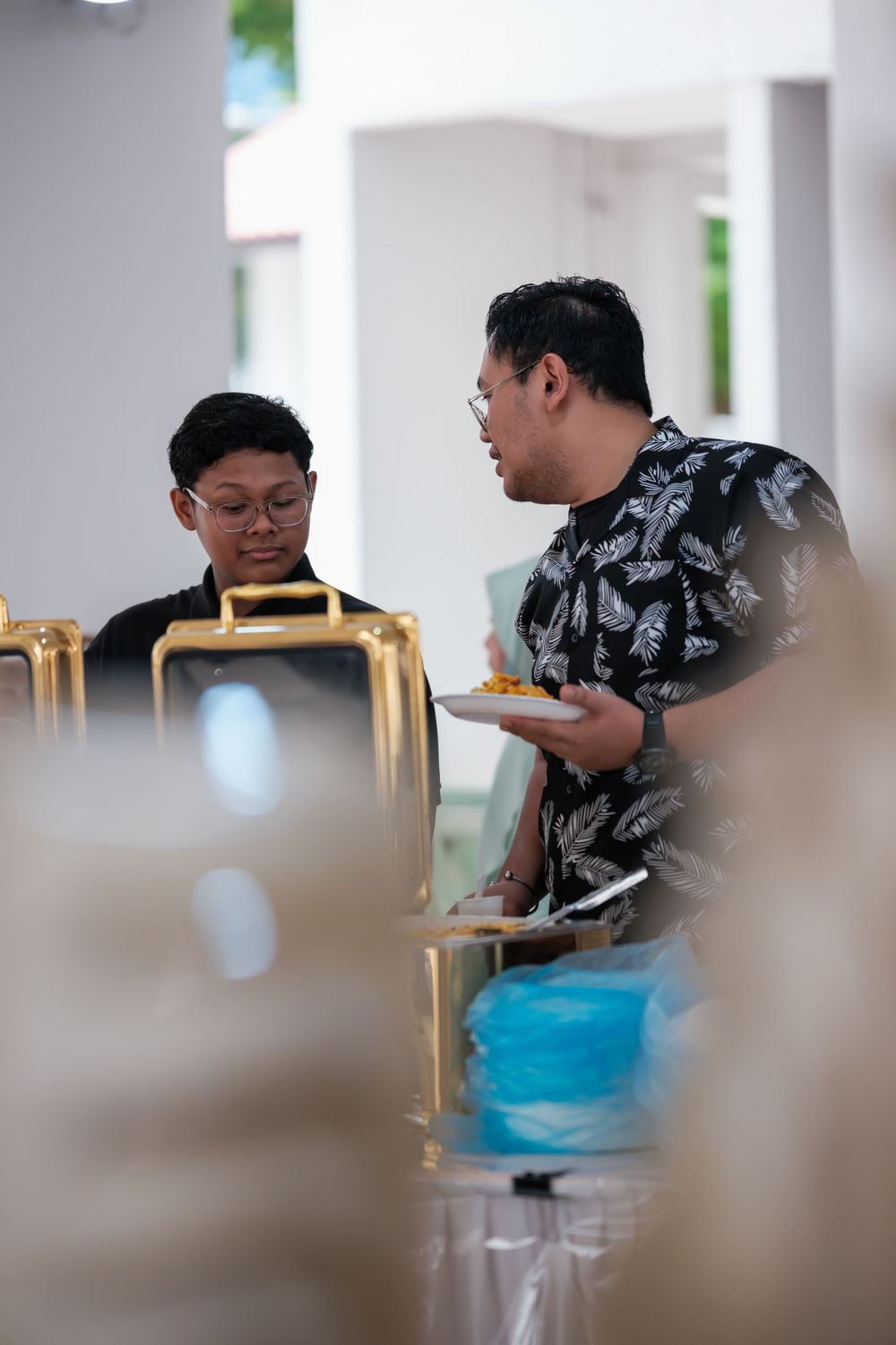 Two guests having a conversation while enjoying food at a wedding reception.