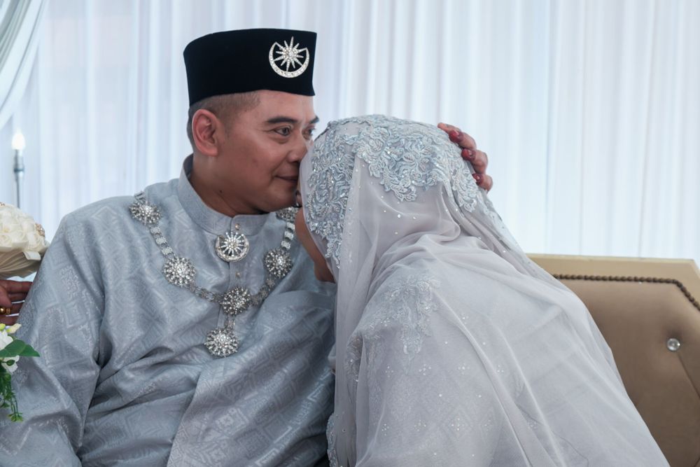 Couple in traditional Malay wedding attire sharing an intimate moment.