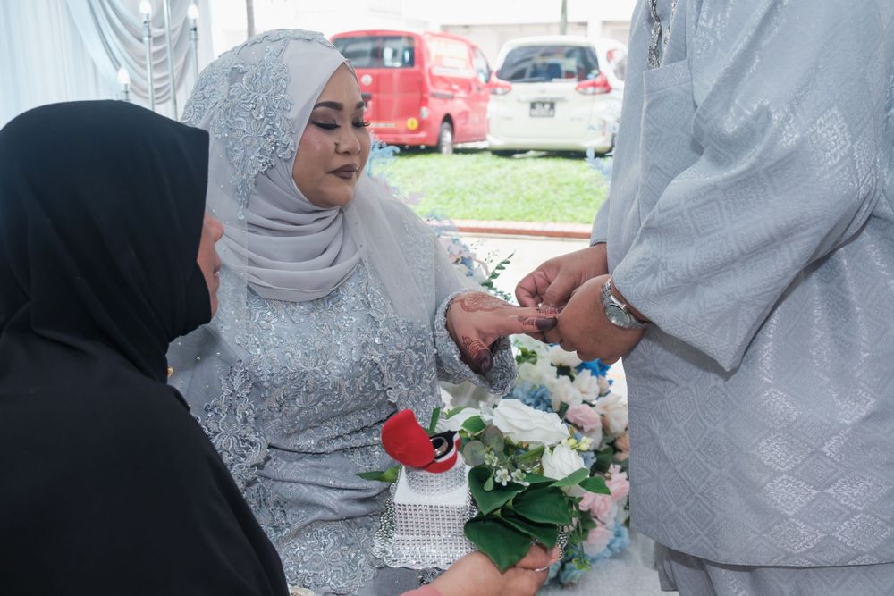 A celebratory moment during a traditional Malay wedding ceremony with floral decorations.