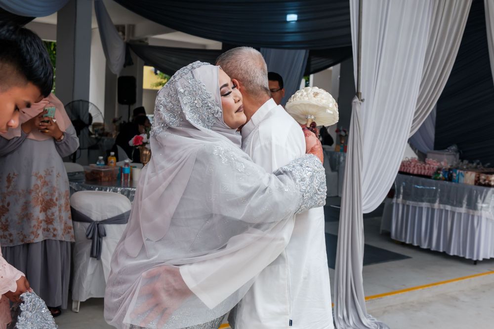 A tender embrace shared during a traditional Malay wedding celebration.