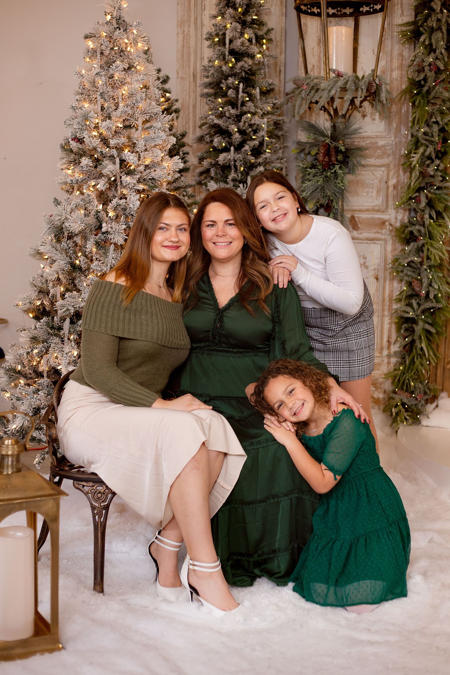 Festive Christmas scene with decorated trees and four people in green and white outfits posing together.