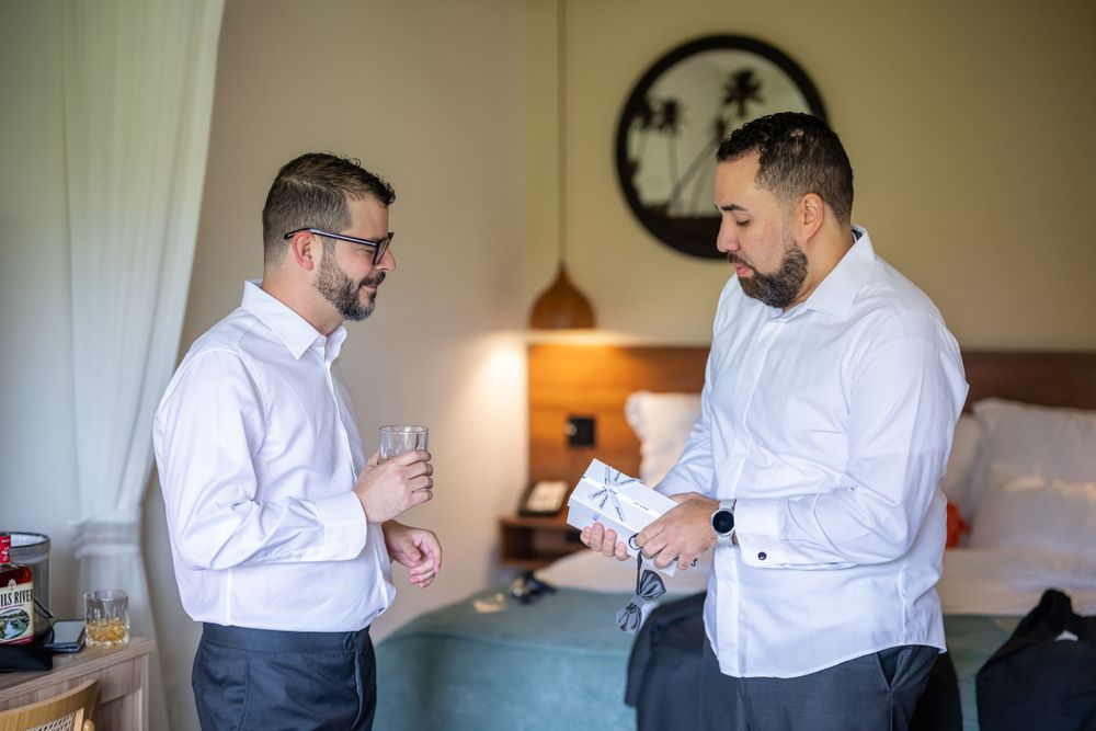 Two people in white dress shirts examining items in a hotel room.