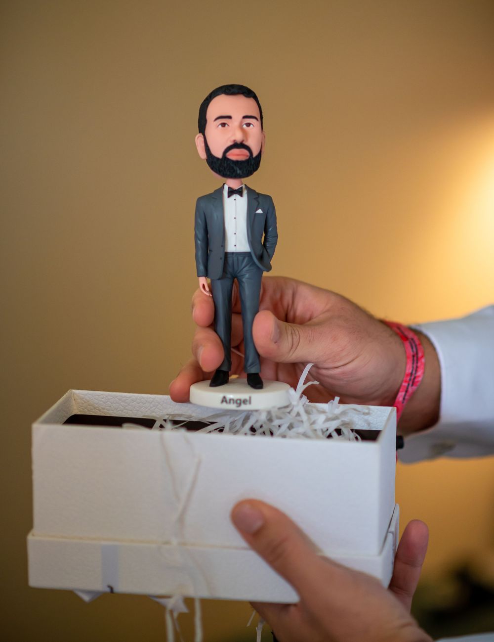 Groom's custom bobblehead figurine being removed from white gift box.