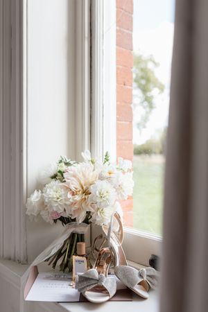 White floral bouquets and wedding details arranged on a sunny windowsill.