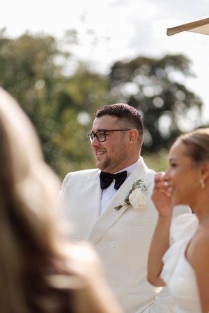 Close up shot of wedding party members smiling during outdoor ceremony.