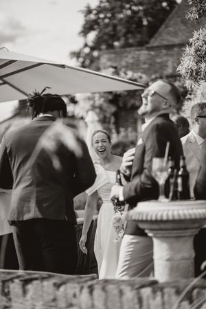 Wedding guests gather under white umbrellas on an outdoor patio during a summer celebration.