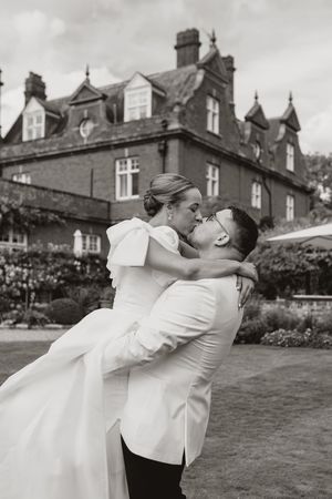 A couple shares a romantic dance moment on the lawn of a historic building.