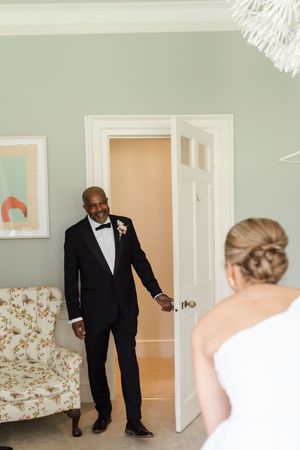 Emotional first look moment between a couple on their wedding day in a bright interior setting.
