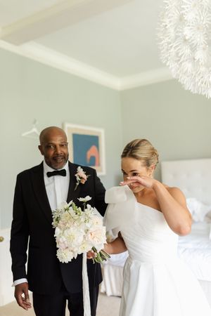 Elegant wedding party preparations in a bright white room with floral bouquets.