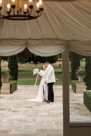 A couple dances under an elegant white tent at their wedding reception.