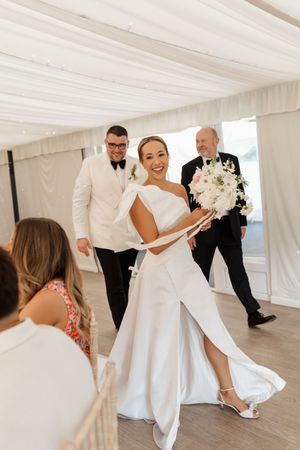 A series of wedding photos showing a bride in a white dress twirling and dancing in an elegant white tent venue.