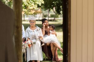 Wedding guests gather outdoors under a covered porch area during celebration.