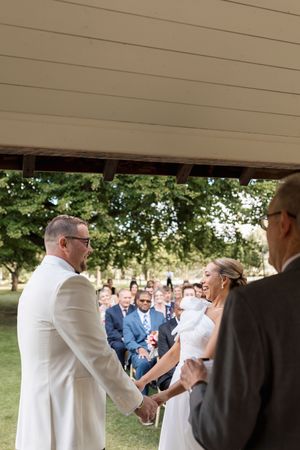 Wedding guests in formal attire mingle and celebrate under a covered outdoor area.