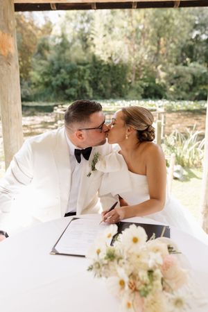 Romantic outdoor wedding ceremony scene with white floral arrangements and natural lighting.