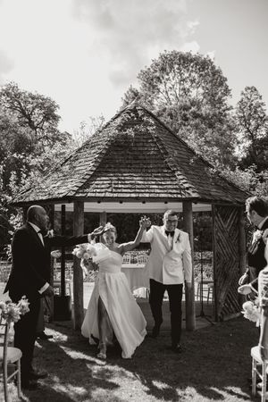 Black and white photo of wedding ceremony moments under a rustic gazebo.