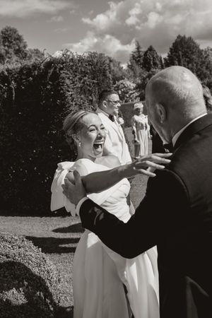 A candid black and white photo capturing a joyous moment of laughter during a wedding celebration.