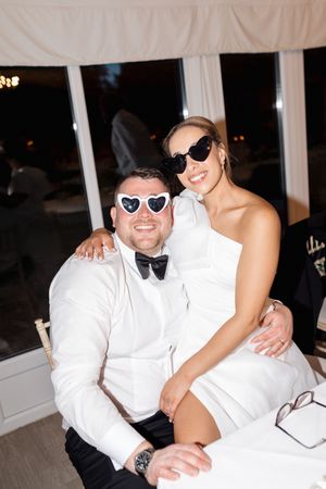 Wedding party members in white formal attire posing together at a reception.