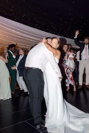 Wedding reception dance floor scene with couples dancing and celebrating in formal attire under starry lighting.