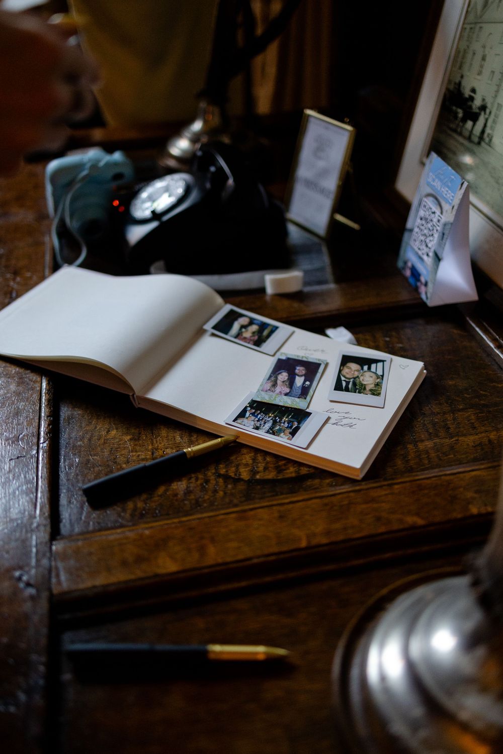 A vintage guestbook with photographs lies open on a wooden table with antique decorative items.