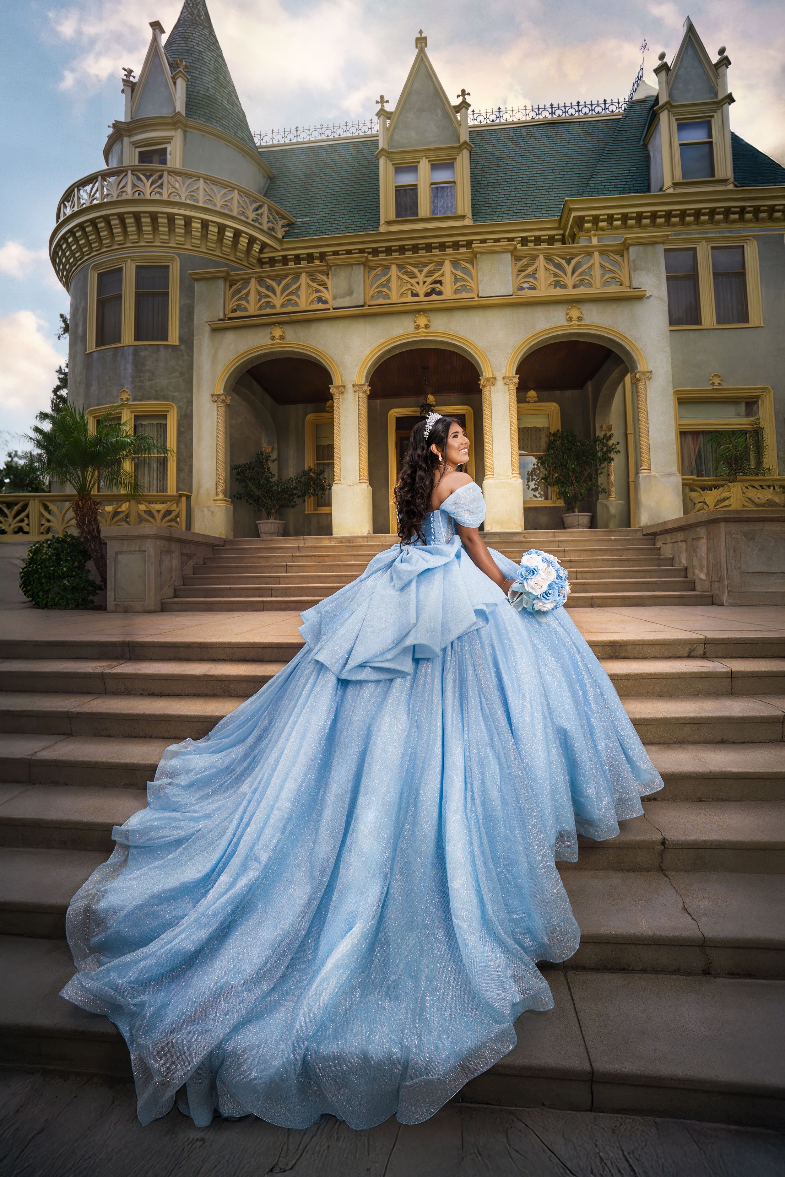 A flowing light blue ballgown dress cascades down ornate mansion steps in a series of elegant outdoor photos.