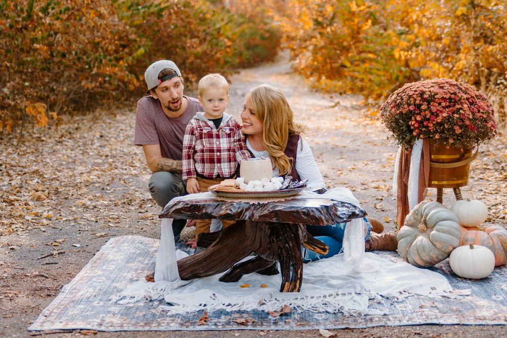 Family having picnic on blanket with fall decorations and pumpkins.