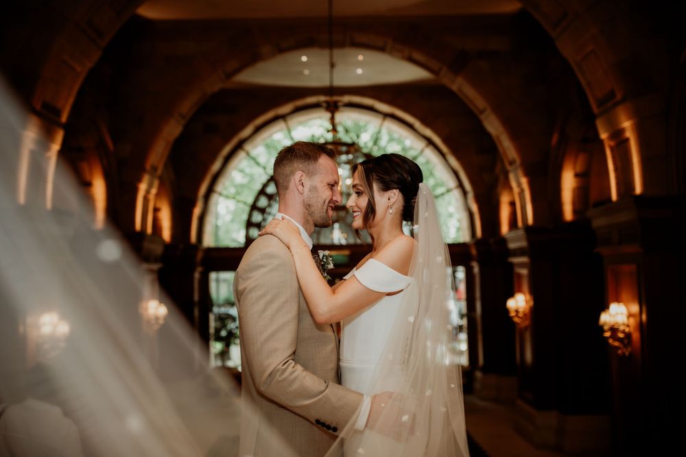 Romantic couple sharing an intimate moment in an elegant stone archway with warm lighting.