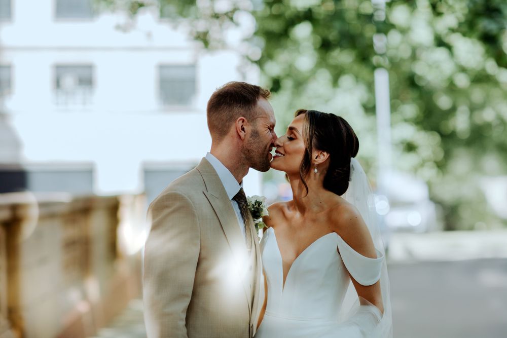 A romantic outdoor wedding moment between newlyweds sharing an intimate embrace in soft natural lighting.