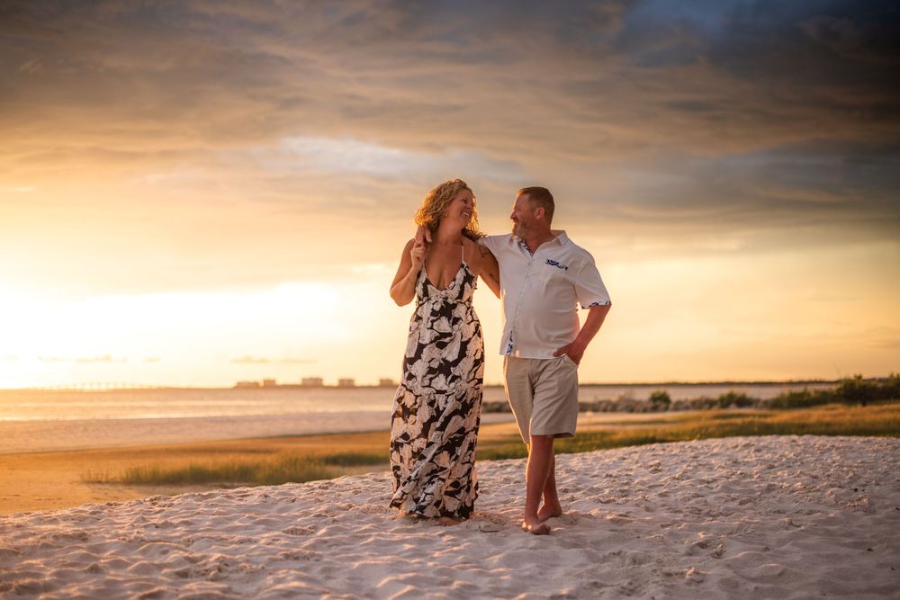 Couple walking on sandy beach during golden sunset hour.