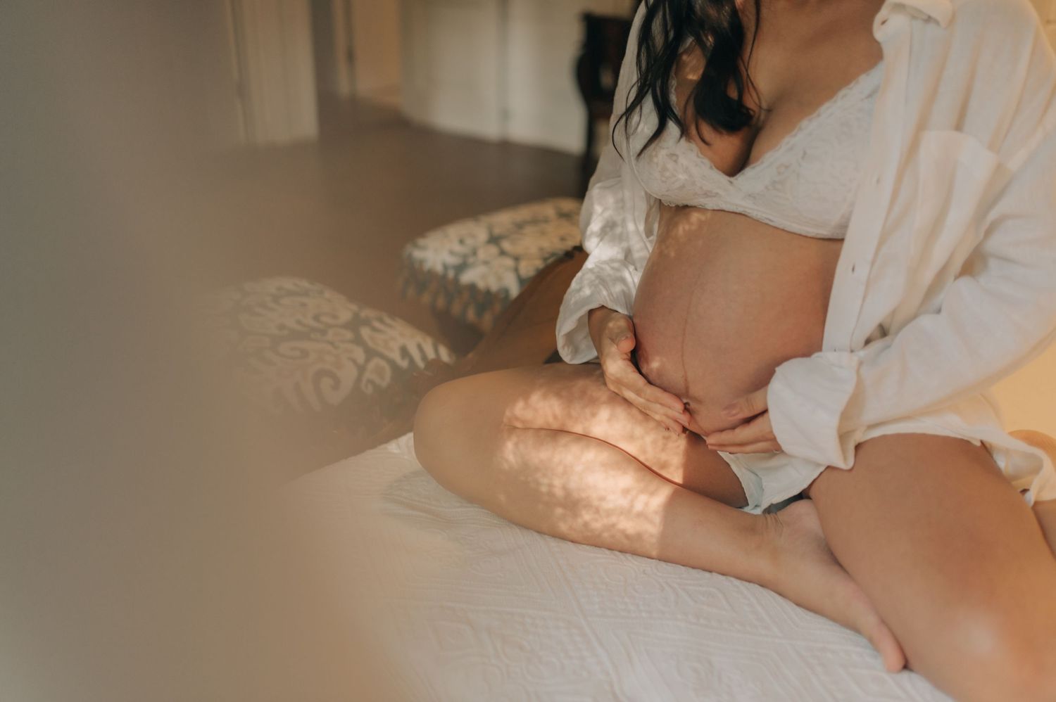 Intimate maternity photo showing pregnant belly in soft natural lighting.