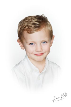 Classic portrait of a child in a white collared shirt with a subtle smile against a light background.