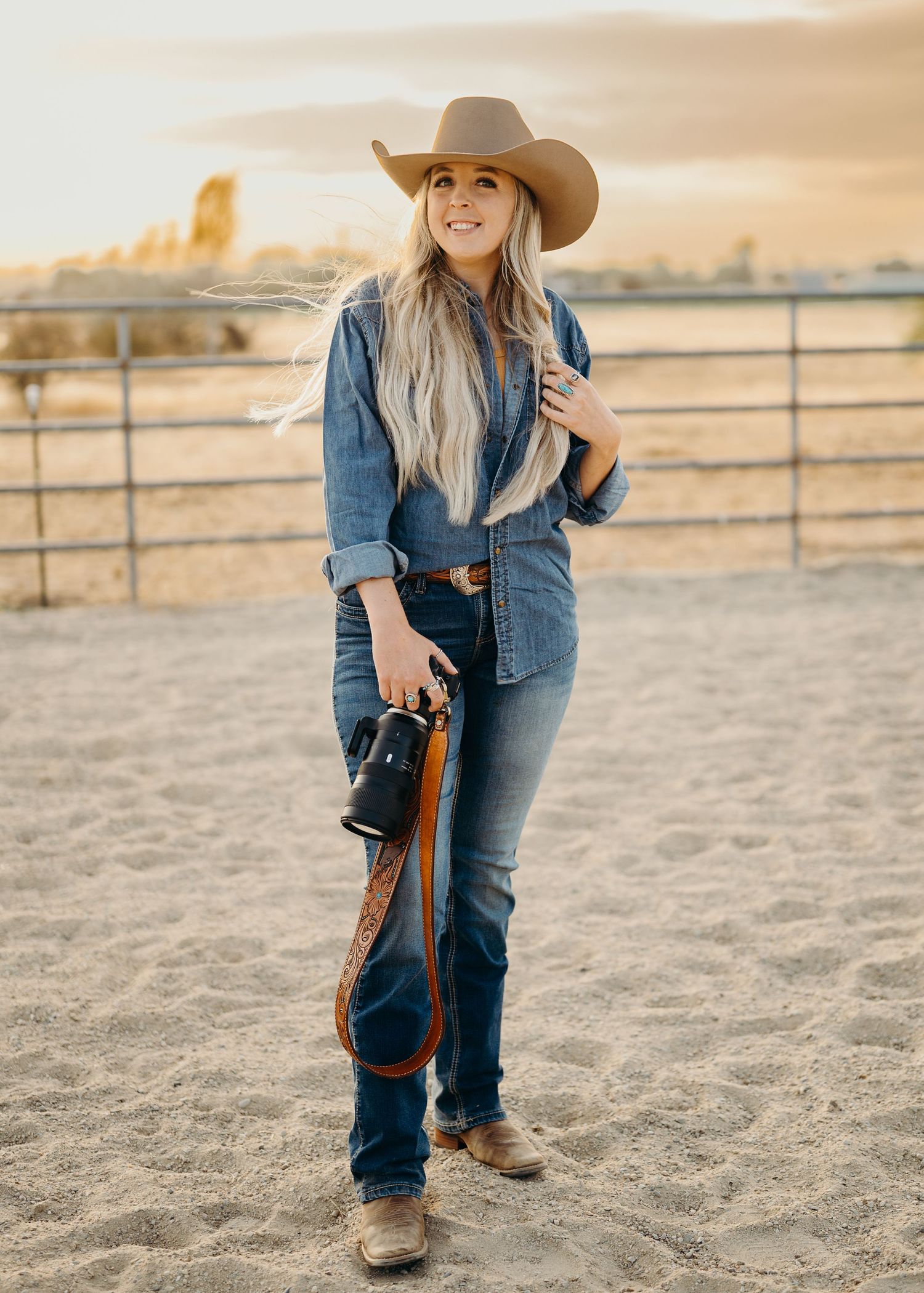 Western-style boots and denim against a sandy arena backdrop at sunset.