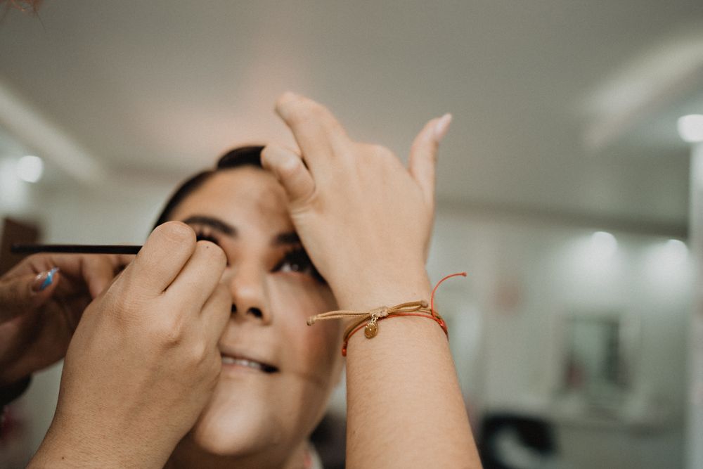Artistic shot of makeup artists’ hands working on the bride, capturing the beauty of wedding preparations