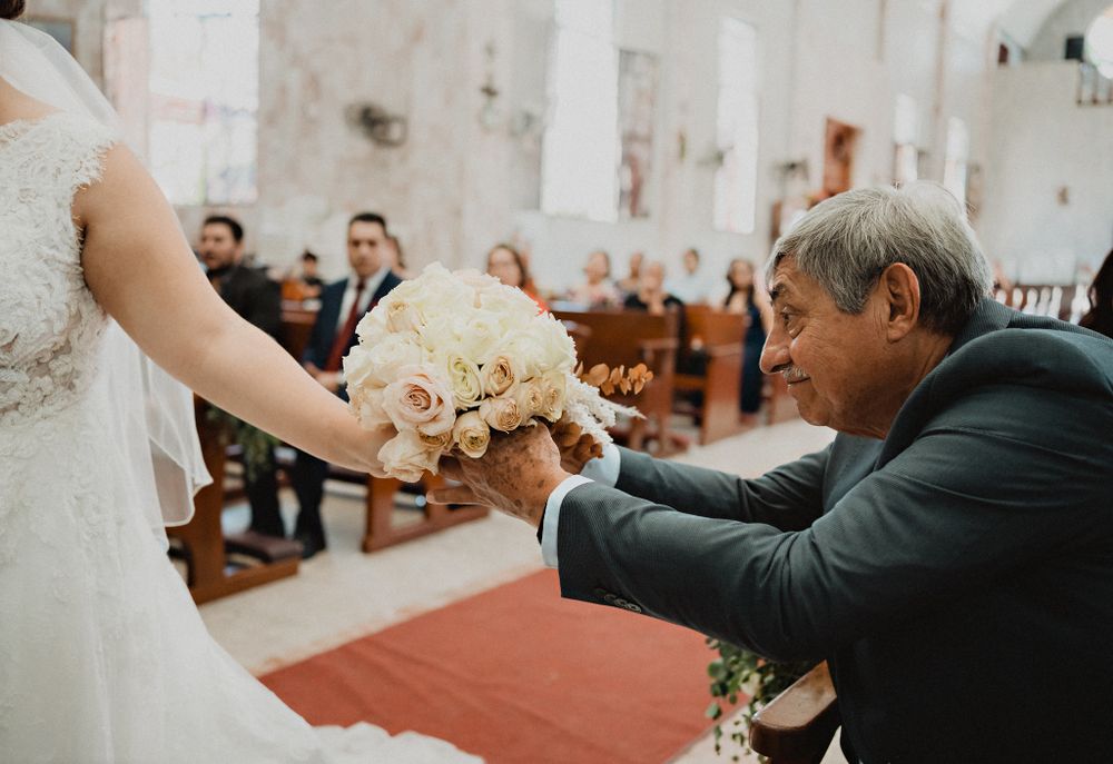 Father helping to hold the bride's bouquet, a sweet moment of fatherly love during the ceremony