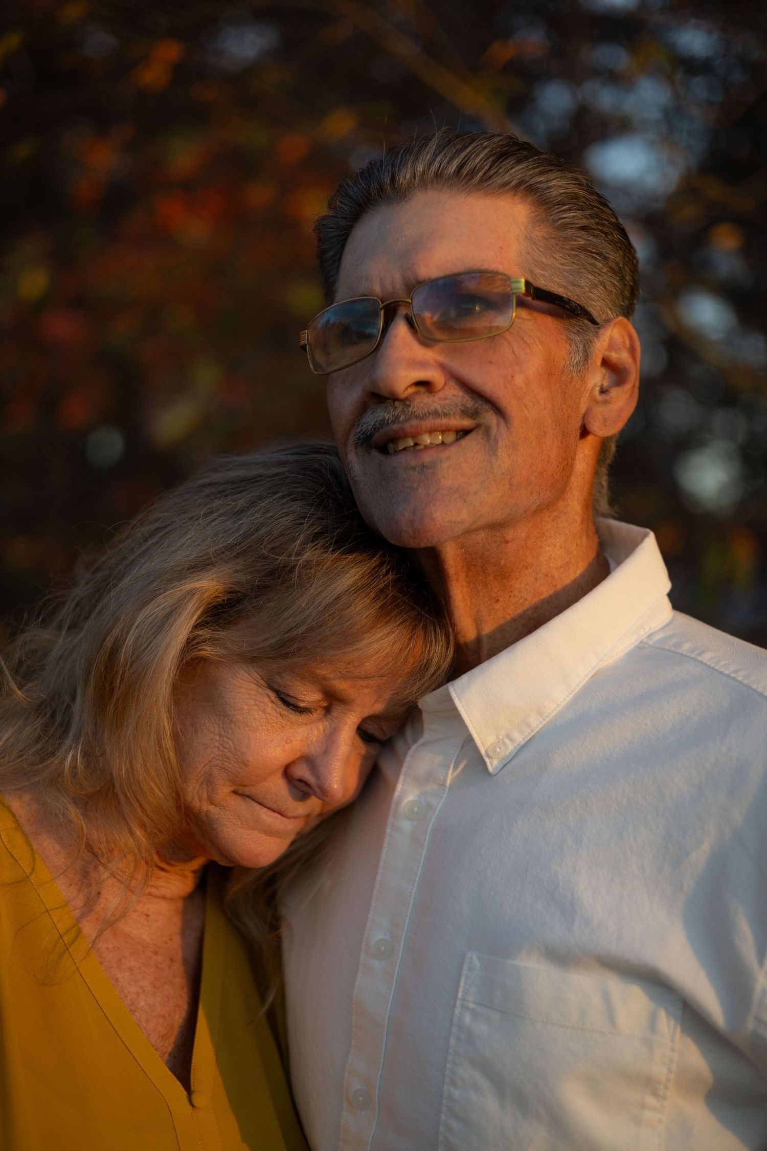 A man looks into the distance while his wife rests her head on his shoulder.