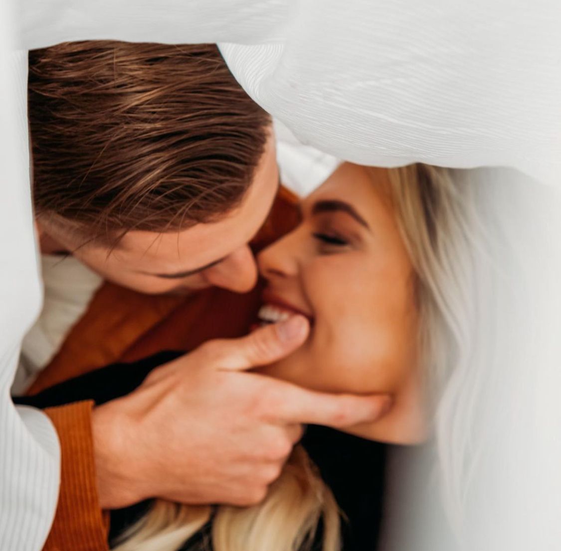 Intimate close-up portrait of couple sharing a tender moment under a veil.
