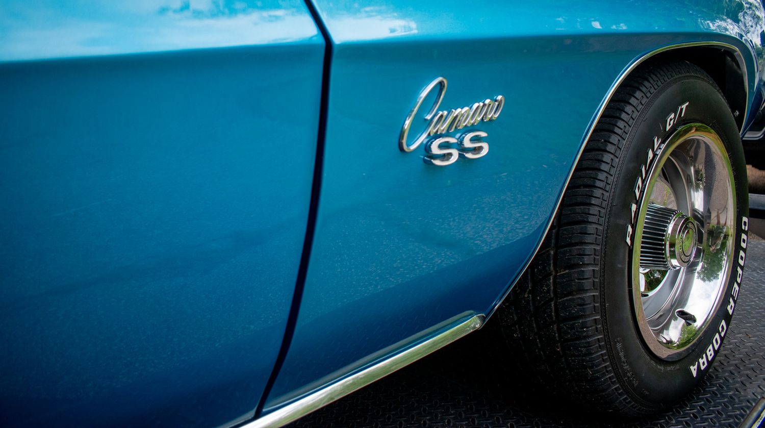 Detail shot of blue Camaro SS badge and chrome trim on vintage muscle car.