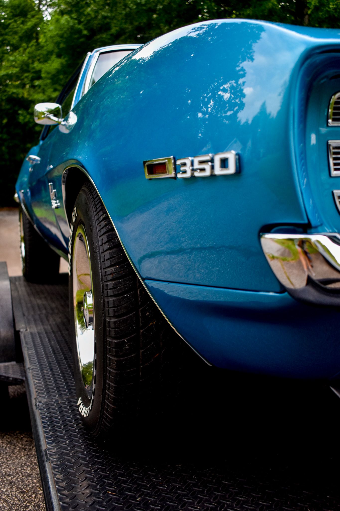 Close-up of a blue classic Camaro 350 badge and wheel well.