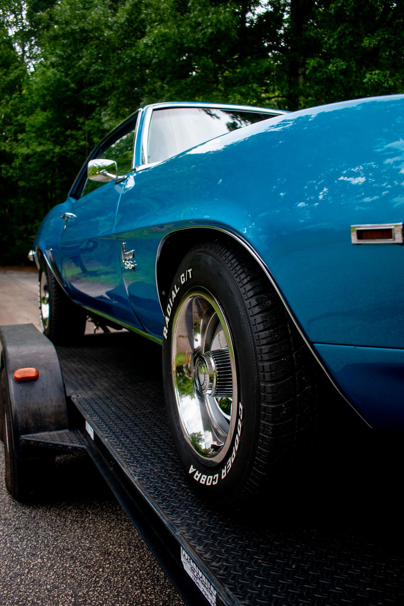 Side profile of blue Chevrolet Camaro on car trailer showing classic muscle car lines.